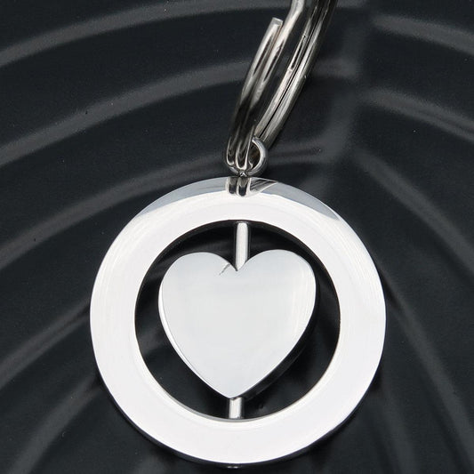 Henkilökohtainen kaiverrettu avaimenperä "Spinning heart", jossa on kaiverrus molemmin puolin nimikirjaimet pariskunnille.